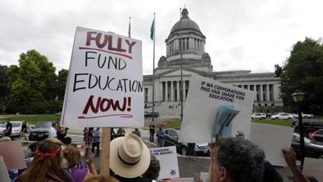 A small group of demonstrators stand on the steps of the Temple of Justice and in view of the Legislative Building as they advocate for more state spending on education prior to a hearing before the state Supreme Court Wednesday, Sept. 3, 2014, in Olympia, Wash. The court ordered lawmakers to explain why they haven't followed its orders to fix the way Washington pays for public education. Lawmakers, the governor and others say the court needs to be patient and give the Legislature more time to fulfill the orders from the 2012 McCleary decision. (AP Photo/Elaine Thompson)
