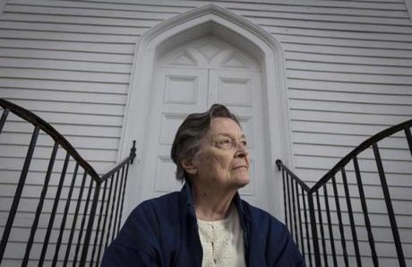 Pat Constantinos sits in front of the St. Paul's Episcopal Church in Otis, Mass. Constantinos is the wife of a former pastor at St. Paul's Episcopal Church that the diocese is planning to close she and others are fighting the move. The interior of the church is locked. She no longer has access to the interior of the building. (Steven G. Smith for The Boston Globe)
