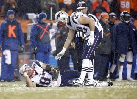 Scott Chandler lends a helping hand to Patriots tight end Rob Gronkowski after Gronkowski suffered a knee injury in last week?s loss to the Broncos.
