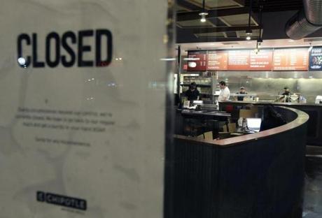 People stood inside a closed Chipotle restaurant on Monday in Cleveland Circle.
