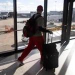 A traveler made his way through a hall way overlooking a tarmac at Logan International Airport. 