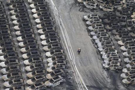 A rescuer walks past damaged cars at the site of the explosions in Tianjin on Aug. 14. Enormous explosions in a major Chinese port city killed at least 44 people and injured more than 500, state media reported on Aug. 13, leaving a devastated industrial landscape of incinerated cars, toppled shipping containers and burnt-out buildings. 
