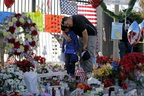 Gary Mendoza, and his son Michael pay their respects at a makeshift memorial site honoring Wednesday's shooting victims on Dec. 7 in San Bernardino, Calif. Thousands of employees of San Bernardino County are preparing to return to work Monday, five days after a county restaurant inspector and his wife opened fire on a gathering of his co-workers, killing 14 people and wounding 21. 
