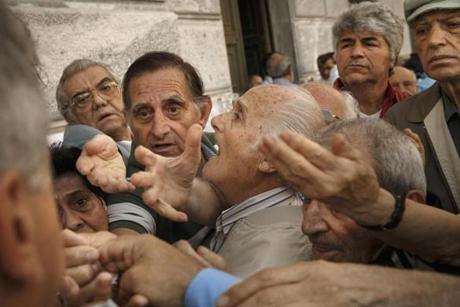 Pensioners try to get a number to enter inside a bank in Athens, on July 1. About 1,000 bank branches around the country were ordered by the government to reopen to help desperate pensioners without ATM cards cash up to 120 euros ($134) from their retirement checks. 
