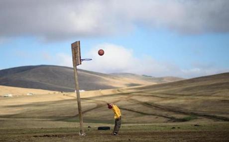 This picture taken on July 8 shows 13-year-old jockey Purevsurengiin Togtokhsuren playing basketball after taking care of the horses in Khui Doloon Khudag, some 50 kms west of Ulan Bator. Despite being only 13 years old, Togtokhsuren is riding for the fifth time in the national races for Mongolia's summer festival, known as Naadam, lining up against some 170 other child jockeys. 

