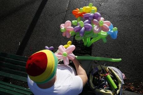 A balloon artist tied up a bunch of flowers on a Christmas day that felt more like Spring as he sat on a bench on the Boston Common wearing a t-shirt in Boston. 
