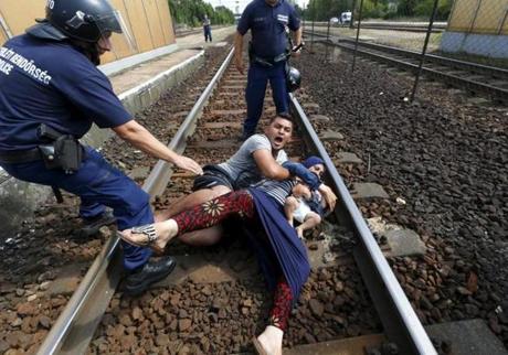 Hungarian policemen stand by the family of migrants as they want to run away at the railway station in the town of Bicske, Hungary, on Sept. 3. 
