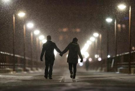 Peter Best and Mackenzie Kuhl hold hands while walking across the Stone Arch Bridge Dec. 28 in Minneapolis. A winter storm is expected to dump up to a foot of snow in south-central Minnesota before it tracks north and east.
