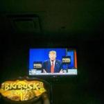 On a television mounted above a hunting video game, Donald Trump speaks during the Republican presidential primary debate at Legends American Grill in Des Moines, Iowa on Thursday.