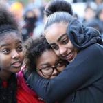 Eden Debebe of Cambridge (left), with Tameica Muir and Jisela Gonzalez, both of Dorchester, tried to keep warm as US Senator Elizabeth Warren spoke at a King Day service event outside Cambridge City Hall on Monday. 