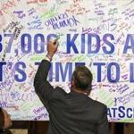Governor Charlie Baker signed a banner after he received 25,000 charter school petition signatures Tuesday.