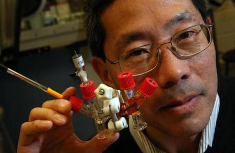 Professor Yet-Ming Chiang posed for a portrait with an H-cell battery in a research laboratory at MIT.

