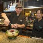 Paul Chen, owner of the Bamboo Cafe in Norwood, makes a scorpion bowl with help from his wife, Emily Xu.