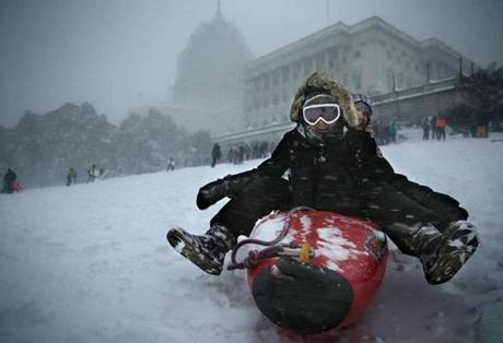 Local Washington D.C. residents Amber Neightengale (left) and Marisa Pace (R) sled down the West Front Lawn of the U.S. Capitol on a kayak. 
