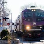 An MBTA commuter rail train fronted by a new locomotive entered West Medford station.