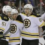 Boston Bruins center Ryan Spooner (51) and defenseman Kevan Miller (86) congratulate teammate Brad Marchand after his goal during the first period of an NHL hockey game against the Detroit Red Wings, Sunday, Feb. 14, 2016, in Detroit. (AP Photo/Carlos Osorio)