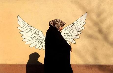 An Iranian woman walks past a graffiti depicting bird wings in downtown Tehran on February 25, 2016. / AFP / BEHROUZ MEHRIBEHROUZ MEHRI/AFP/Getty Images
