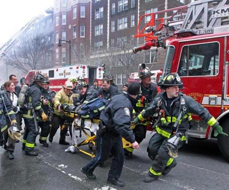 03/26/14: Boston, MA: A nine alarm fire broke out this afternoon at 298 Beacon Street. Frantic fire fighters scream for an ambulance as they work on and rush an injured fire fighter on a stretcher down Beacon Street. (Jim Davis/Globe Staff) section: metro topic:27fire(3)
