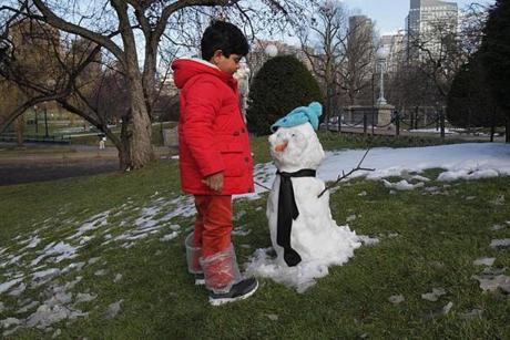 Ibrahim Bawazeer, 6, who was visiting Boston from Saudi Arabia and saw snow for the first time, inspected a snowman left on the Public Garden. By late afternoon, the snow was mostly gone.
