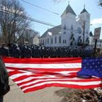 Spectators held a flag as members of the State Police lined up during the funeral for Massachusetts State Trooper Thomas Clardy at St. Michael?s Catholic Parish in Hudson on Tuesday. 