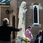 Norwood, MA - 3/27/2016 - A parishioner touches pray a statue of Mary that was vandalized at St. Catherine's Catholic Church in Norwood, MA, March 27, 2016. (Keith Bedford/Globe Staff)