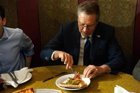 Presidential candidate John Kasich eats a slice Wednesday at Gino's Pizzeria and Restaurant in Queens, N.Y.
