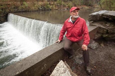 Ken Egnaczak sat on a wall by the small backyard dam that he is trying to get approval to repower.
