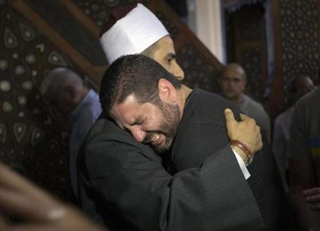 The Imam of al Thawrah Mosque, Samir Abdel Bary, embraces Tarek Abu Laban, center, following prayers for the dead in Cairo, Egypt on Friday, May 20, 2016. Abu Laban lost four relatives in Thursday's EgyptAir plane crash. The Airbus A320 was flying from Paris to Cairo when it disappeared over the Mediterranean Sea. (AP Photo/Amr Nabil)
