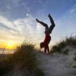 Wellfleet, MA- July 1, 2014- Globe Staff Photo by Stan Grossfeld- Damon Wolf, 13, New Paltz, N.Y. does a handstand as the sun sets into Cape Cod Bay in Wellfleet.Damon Wolf, 13, New Paltz, N.Y. â??The sun kind of got low enough in the sky and it just illuminated everything and the colors of the dunes were really saturated and really popped out at me and looked awesome. It just made me extremely happy. I love life, life is awesome. This is such a beautiful place to be in the entire world. Seeing the sun and looking out over the ocean and its just endless power it just makes everything look surreal and amazing and beautiful.â??