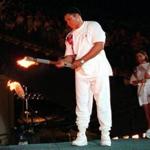 FILE - In this July 19, 1996, file photo, American swimmer Janet Evans looks on as Muhammad Ali lights the Olympic flame during the 1996 Summer Olympic Games opening ceremony in Atlanta. Ali, the magnificent heavyweight champion whose fast fists and irrepressible personality transcended sports and captivated the world, has died according to a statement released by his family Friday, June 3, 2016. He was 74. (AP Photo/Michael Probst, File)