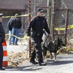 A Rhode Island State Trooper escorts a dog as they exits a dig behind a mill complex at the intersection of Branch Ave. and Woodward Rd., in Providence, R.I., looking for human remains Wednesday, March 30, 2016. (Photo/Stew Milne for the Boston Globe)