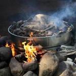 A roaring fire heats a burlap-covered steel tub filled with lobsters, clams, corn, potatoes, sausages, and more. 