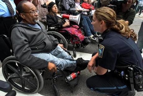 A Boston police officer spoke with Mr. Brooks on May 21, 2012, as a group gathered in front of the State House to demonstrate against fare increases for The Ride.
