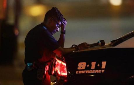 A Dallas police officer, who did not want to be identified, takes a moment as she guards an intersection in the early morning after a shooting in downtown Dallas, Friday, July 8, 2016. At least two snipers opened fire on police officers during protests in Dallas on Thursday night; some of the officers were killed, police said. (AP Photo/)
