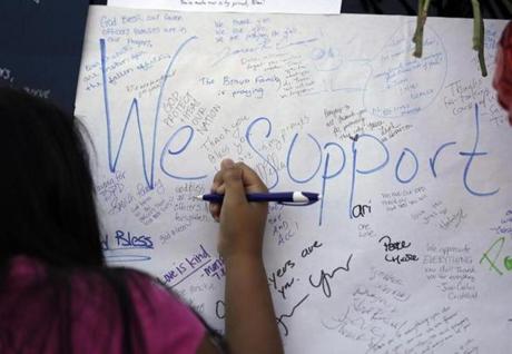 Jasmine Ruiz writes a note at a make-shift memorial in front of the Dallas police department on Saturday.
