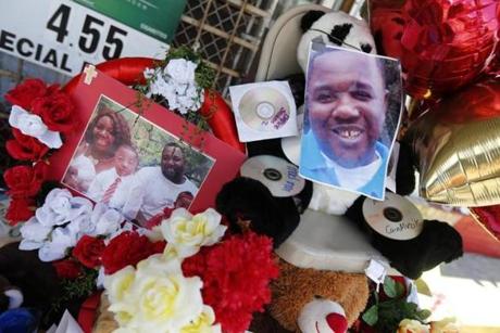 Photos of Alton Sterling are interspersed with flowers and mementos at a makeshift memorial in front of the Triple S Food Mart in Baton Rouge, La., Thursday, July 7, 2016. Sterling, 37, was shot and killed outside the convenience store by Baton Rouge police, where he was selling CDs. (AP Photo/Gerald Herbert)
