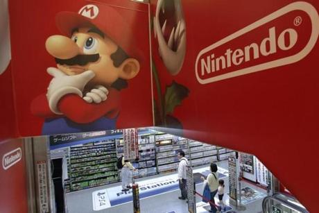 FILE - In this May 7, 2014, file photo, shoppers walk under the logo of Nintendo and Super Mario characters at an electronics store in Tokyo. Nintendo announced July 14, 2016, that it was bringing back its classic Nintendo Entertainment System for fall 2016. (AP Photo/Shizuo Kambayashi, File)
