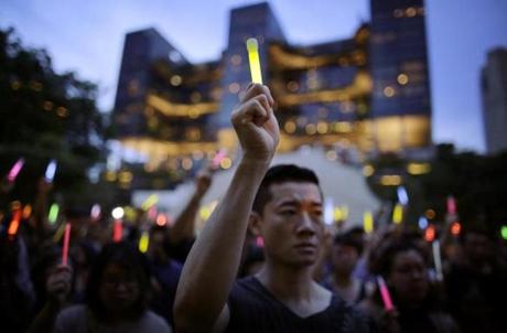 People raised glow sticks, since open flames are banned in Singapore parks, as they gather for a vigil in remembrance of the Orlando shooting victims on Tuesday, June 14. 
