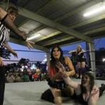 Wrestler Nikki Valentine put Davienne into a hold during a match, while outside the ring, Vanity Vixsin looked on. 