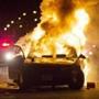 A car burns as a crowd of more than 100 people gathers following the fatal shooting of a man in Milwaukee on Saturday.