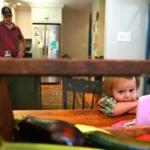 Nina Bagby, 1, who had an elevated lead level, hangs out in the kitchen of her family?s home with her dad close by. 