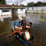 Paul Labatut carried some of his furniture to higher ground Sunday through floodwaters outside his home in St. Amant, La.