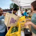 Angela Beyer (right) helps out a customer at Stonehill College's Mobile Market in Brockton.