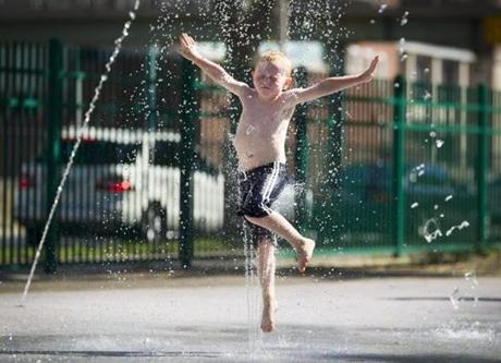 8/14/16 - Boston, MA - Alfond Spray Deck - Cedric Arthur, cq, 5, of Hopedale, MA enthusiastically leapt through fountains at the Alfond Spray Deck on the Esplanade in Boston on Sunday, August 14, 2016 after visiting the Museum of Science with his family. The heat index hit 100 degrees for Boston by mid-afternoon. Photo by Dina Rudick/Globe Staff
