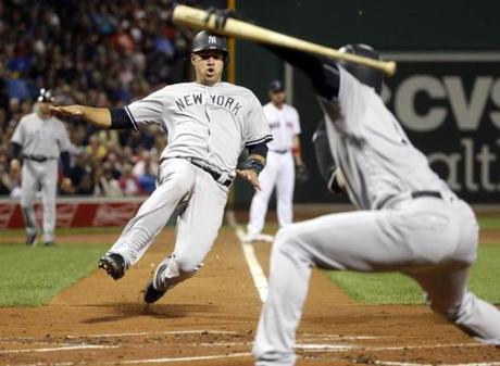 New York Yankees' Gary Sanchez slides while scoring on a sacrifice fly by Billy Butler, as teammate Didi Gregorius, right, signals to him during the first inning of a baseball game against the Boston Red Sox at Fenway Park, Thursday, Sept. 15, 2016, in Boston. (AP Photo/Elise Amendola)
