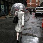 A woman carried an umbrella as light rain fell Monday in Downtown Crossing.