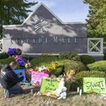 Chris Nelson of Burlington, Wash., takes a picture of a memorial on Sunday Sept. 25, 2016, in Burlington, to five victims killed in a shooting on Friday at a Cascade Mall. The 20-year-old man suspected of killing the five people with a rifle at a Macy's makeup counter had a string of run-ins with the law in recent years, including charges he assaulted his stepfather. (AP Photo/Stephen Brashear)