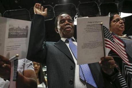 Adison Soko of Derry, N.H., formerly of Zimbabwe, raised his hand for an oath during a citizenship ceremony at the New Hampshire Institute of Politics at Saint Anselm College.
