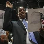 Adison Soko of Derry, N.H., formerly of Zimbabwe, raised his hand for an oath during a citizenship ceremony at the New Hampshire Institute of Politics at Saint Anselm College.