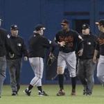 Umpires Ted Barrett, from left, David Rackley, Baltimore Orioles manager Buck Showalter, Orioles' Adam Jones, umpire Eric Cooper and Orioles' Hyun Soo Kim talk after a can was thrown onto the field during play following the seventh inning of an American League wild-card baseball game against the Toronto Blue Jays in Toronto, Tuesday, Oct. 4, 2016. (Mark Blinch/The Canadian Press via AP)
